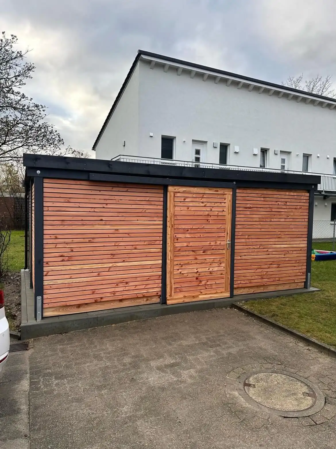 Gerätehaus mit Lärchenholz-Verkleidung und dunklem Rahmen