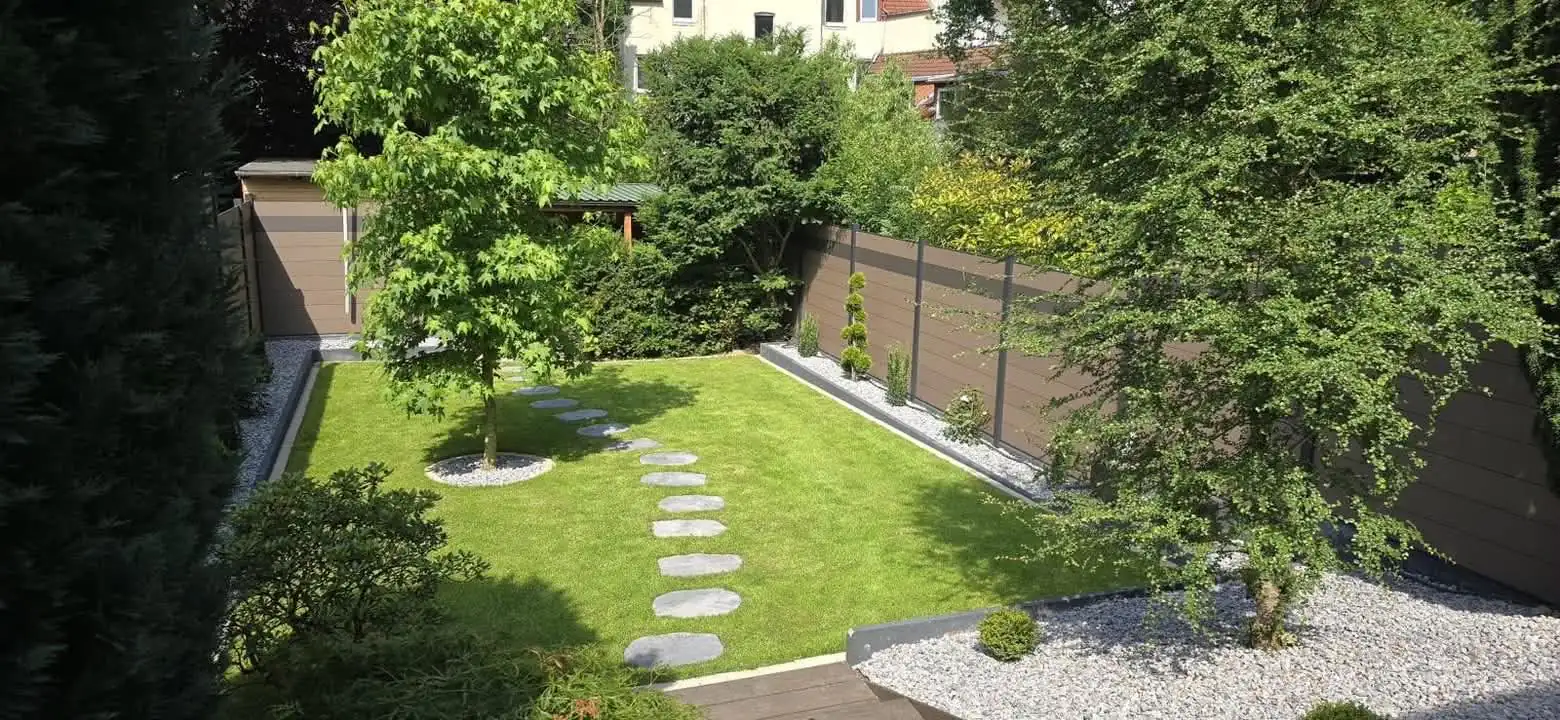 Fertiggestellter Garten mit Rasen, Trittplatten, Kiesstreifen und WPC-Sichtschutz